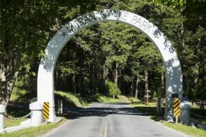 The archway entrance to Moran State Park over a highway and flanked by trees.