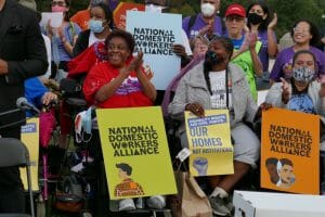 A group of people holding signs about domestic workers rights. 