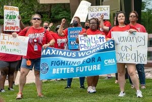 A group of people are holding placards and a banner that states: Maximus workers: fighting for a better future
