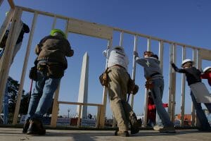 WASHINGTON - NOVEMBER 11: Volunteers raise a wall on a Habitat for Humanity home being built during Operation Home Delivery November 11, 2005 in Washington, DC. During the course of the build, 51 houses will be built on the National Mall, representing each U.S. state and the District of Columbia. The build is in response to the need for housing after Hurricanes Katrina and Rita ravaged the Gulf Coast. (Photo by Joe Raedle/Getty Images)