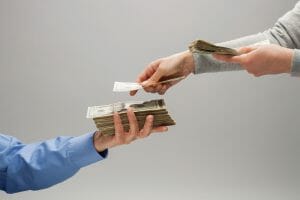 Woman's hands placing US paper currency into man's hand