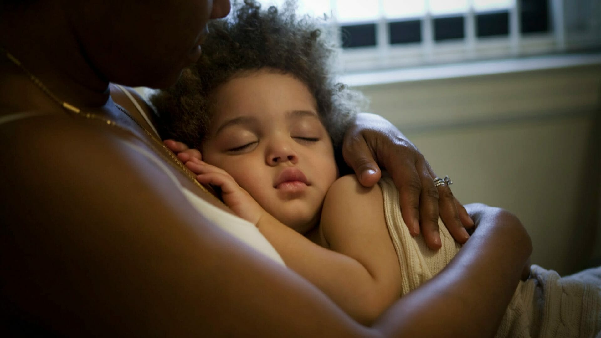 A sleeping child held by a caretaker