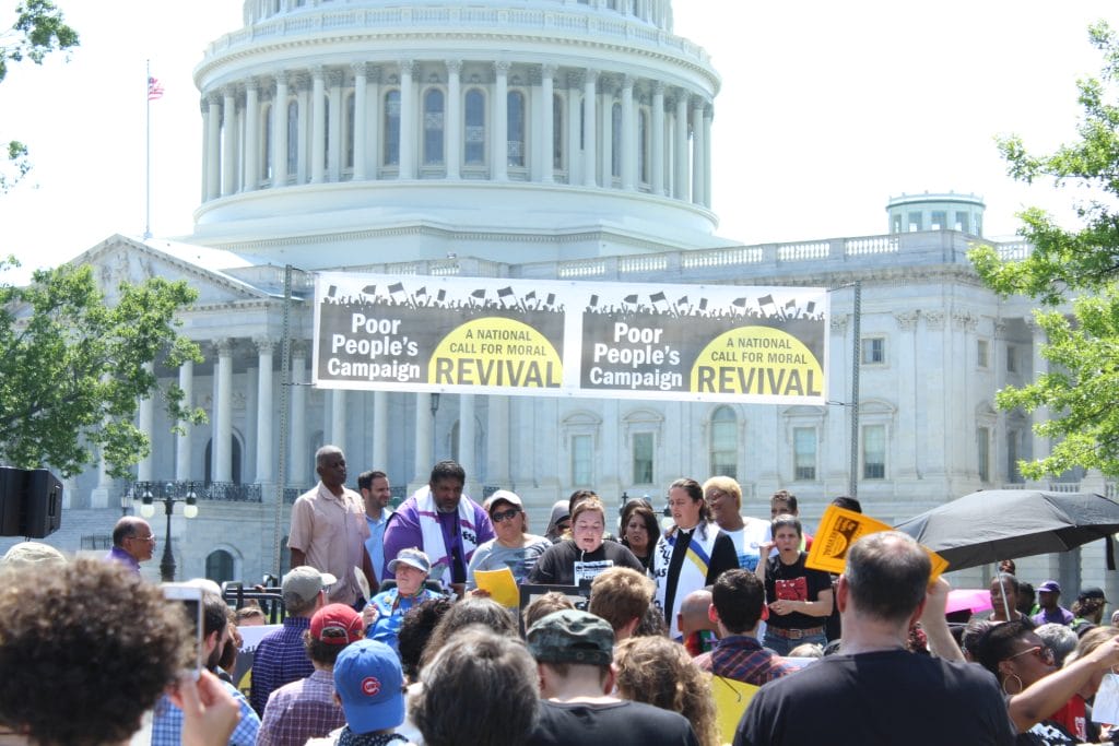 A group of people stand in front of the US Capitol.