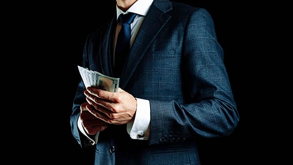 Picture of a man in a suit counting money.