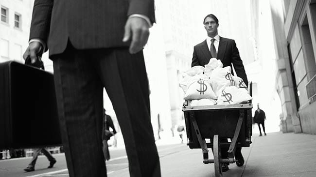 A man with a wheelbarrow full of dollar bags