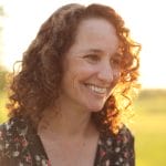 A woman with curly hair is smiling toward the camera
