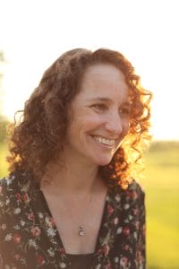 A woman with curly hair is smiling toward the camera