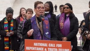 A Black woman speaks at a microphone