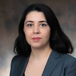 A woman with black hair and gray suit.