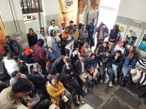 A group of people sit on chairs in a crowded room