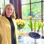 woman in a yellow coat by yellow tulips
