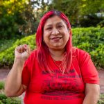 A woman with bright red hair raising her fist.